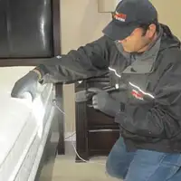 Bed bug inspection technician checking a mattress and bed frame for signs of infestation in Boulder, CO