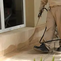 General pest control technician spraying exterior perimeter around a home in Boulder, CO
