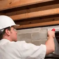 Termite inspection technician checking a basement wall and framing for termite activity in Boulder, CO